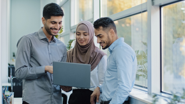 three-smiling-workers-stnading-looking-at-laptop